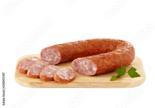 Obraz na płótnie Sliced smoked sausage on wooden cutting board with parsley, cooked meat links is