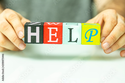 Photos Hands hold and spell out HELP with alphabet blocks, signifying assistance or support