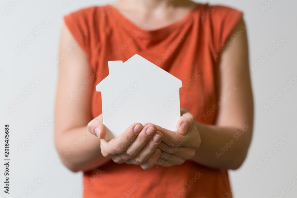 Obraz premium Person's hands cradle a small white house shape representing home ownership