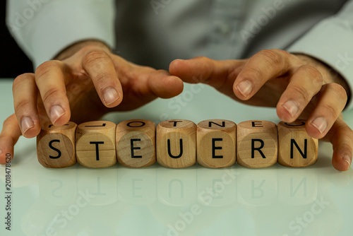 Tableau sur toile Hands hover over wooden cubes forming the German word for taxes