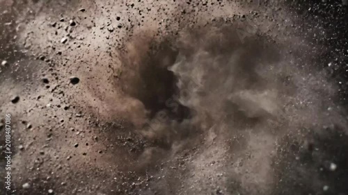 Abstract macro shot of exploding black dust and stone particles swirling in slow motion against a dark background.