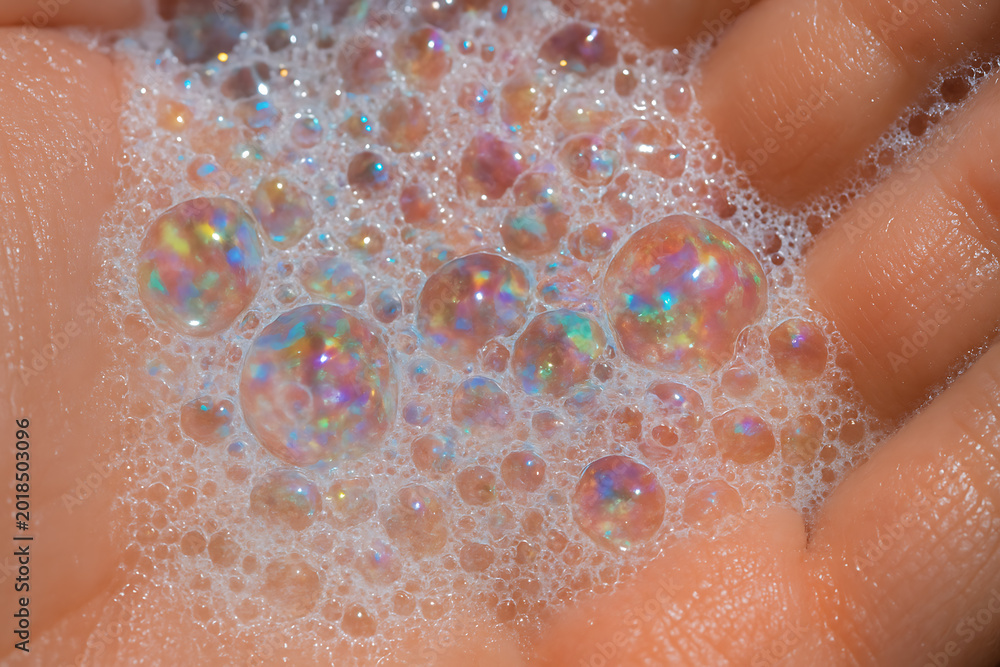 Fototapeta premium Macro closeup of colorful soap bubbles in human hands with iridescent reflections