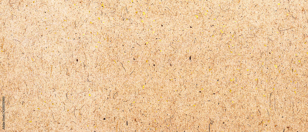 Fototapeta premium Close up of a light brown textured paper background with small dark fibers and yellow flecks, rustic craft paper surface
