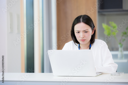 Obraz na plátně A woman in business casual attire, sitting at her computer, struggling with multitasking and feeling overwhelmed during the busy season or while managing a heavy workload—a typical business scenario
