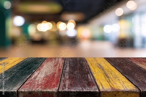 Rustic wooden table with blurred colorful indoor background