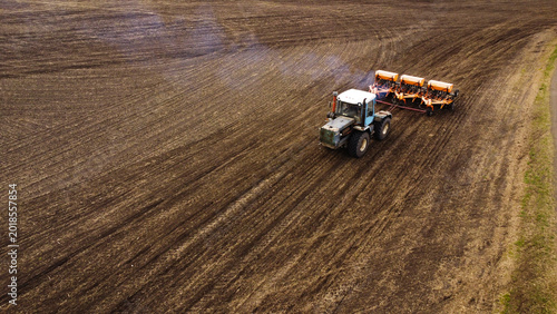 Foto Aerial View of a Tractor Pulling a Seeder with Exhaust Smoke in a Tilled Field