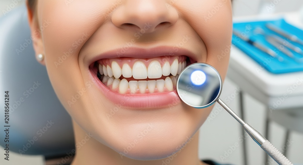 Fototapeta premium Close-up of a bright white smile during a dental checkup. Healthy teeth and gums being examined with a dental mirror in a professional clinic setting. Perfect for dental care content.
