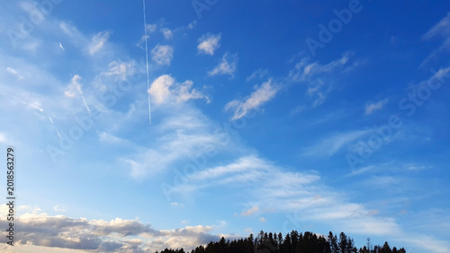 A landscape of green earth and trees against a blue summer sky.