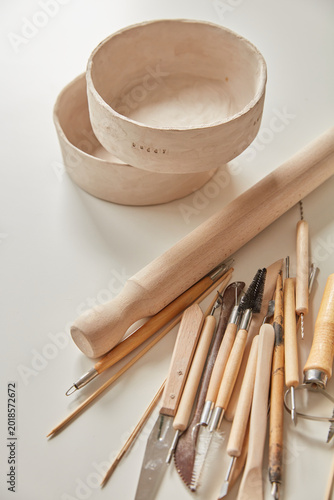 Ceramic Pottery Tools and Handmade Clay Bowls on a White Surface