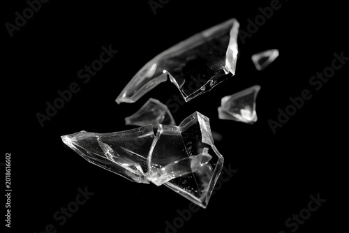 Tableau sur toile Broken transparent glass shard isolated on a black background, with sharp cracked edges, glossy reflections, and dramatic high-contrast studio lighting