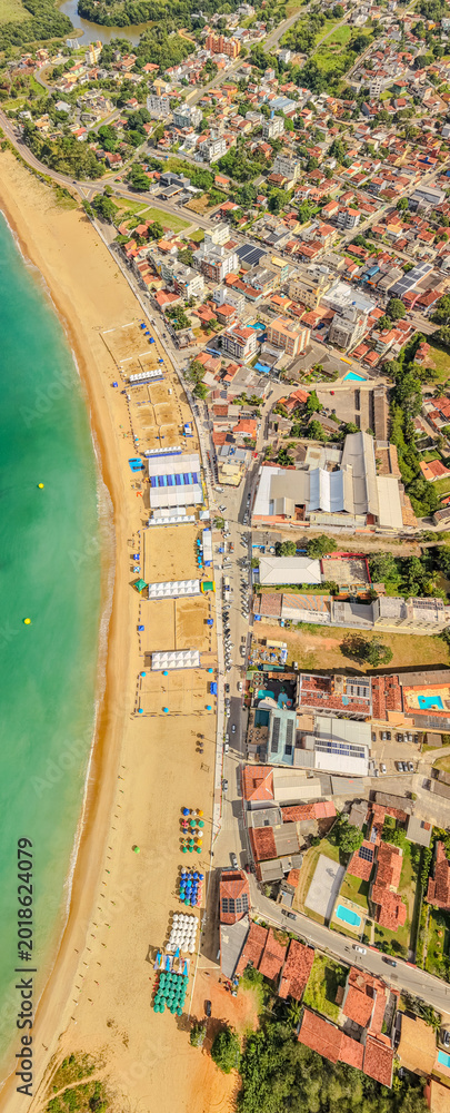 Fototapeta premium Aerial drone panorama of Meaipe Beach during the Brazilian university games in Guarapari, Espírito Santo, Brazil. Tropical coastline with event structures, ocean and summer scenery.