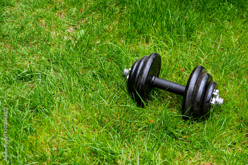 Dumbbells on green grass background. Fitness and healthy lifestyle concept. Fitness equipment on the grass. Bodybuilding