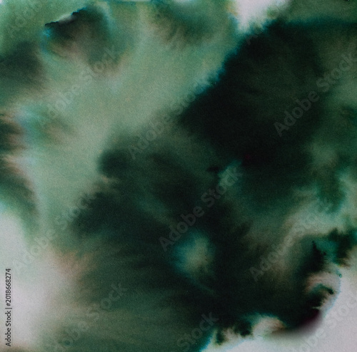 Green watercolor ink spreading and blending on textured paper creating an organic, abstract pattern with varying shades and soft transitions, depicting fluidity and natural elements