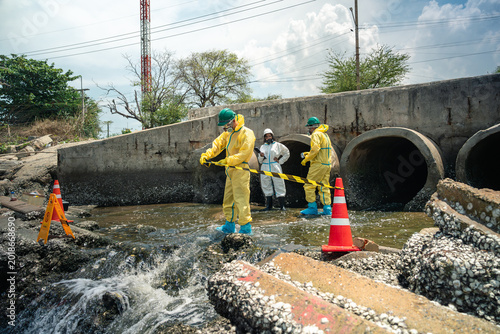 Environmental Workers Conducting Industrial Wastewater Inspection Near Coastal Drainage Site For Pollution Monitoring And Environmental Compliance Reporting Activity Outdoors