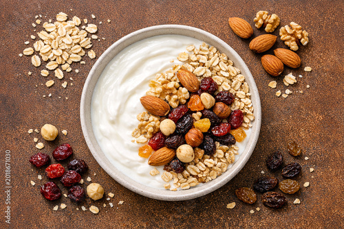 Delicious bowl of yogurt with granola, nuts, and berries on a rustic table top.