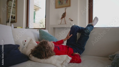 Canvas Print Child lying back on living room sofa resting quietly with relaxed posture, creat