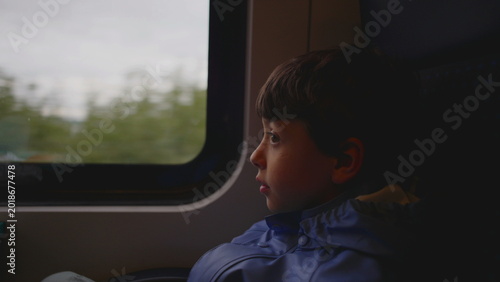 Foto Young boy sits by train window gazing at landscape passing outside creating thou