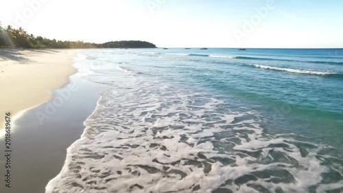 Tranquil beach scene with crystal clear ocean waves gently washing ashore on a sunny day