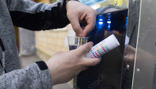Quadro su tela Man checking water quality at a public vending machine using a test strip