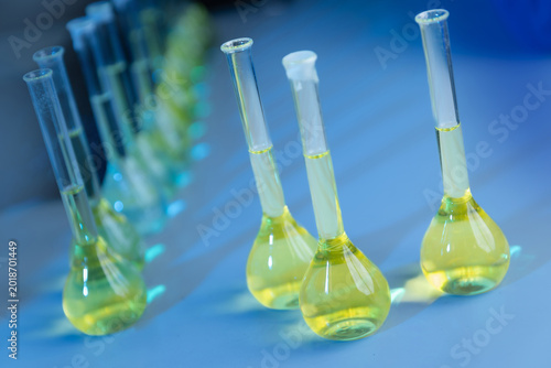 Tableau sur toile Laboratory flasks containing yellow liquid on blue table