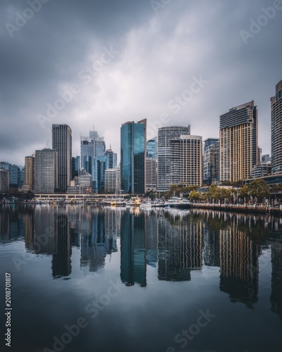 City Skyline Reflection on Water Under Cloudy Sky