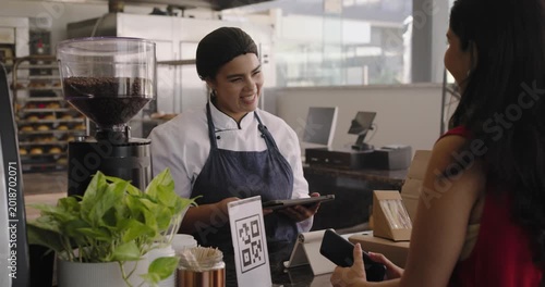 Chef in coat tapping POS African American customer showing phone to pay handing package at counter