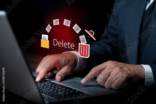 Businessman using computer, he presses the delete button on the computer keyboard. Trash can and files. Delete files