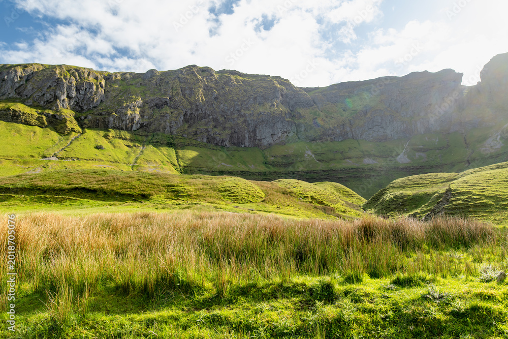 Naklejka premium Gleniff Horseshoe in County Sligo, Ireland, with rolling grassland beneath steep limestone mountains and bright clouds. A scenic drive through one of Irelands classic valleys.