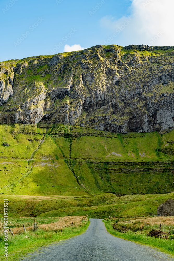Obraz premium Gleniff Horseshoe in County Sligo, Ireland, with rolling grassland beneath steep limestone mountains and bright clouds. A scenic drive through one of Irelands classic valleys.