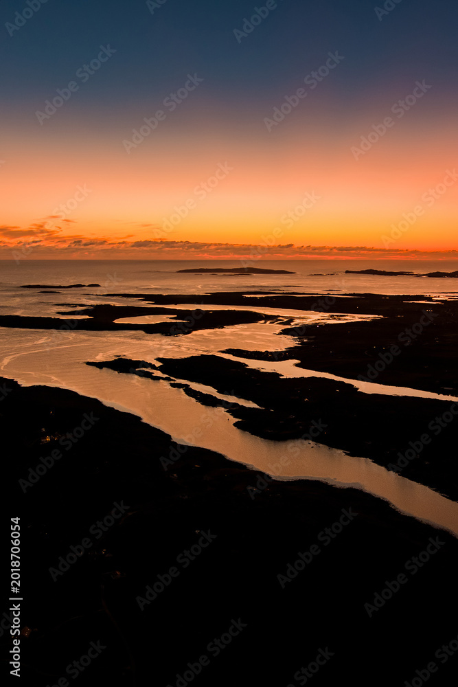 Fototapeta premium Sunset glows over Clifden Bay and the Atlantic islands from the Sky Road viewpoint in Connemara, County Galway. Aerial scenic view from one of Irelands best coastal lookouts. Wild Atlantic Way.