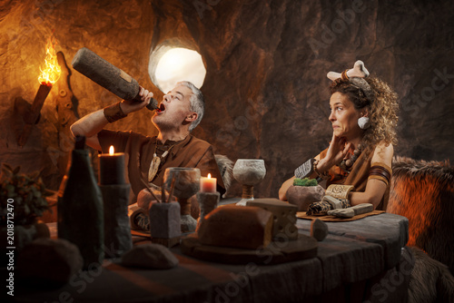 Bild auf Leinwand Rude Caveman Drinking from Bottle During Date – Prehistoric Bad Manners and Rela