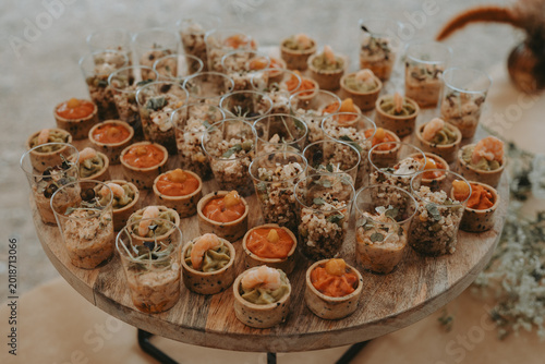 Fotografie Assortiment de bouchées apéritives et verrines sur un plateau en bois lors d'un