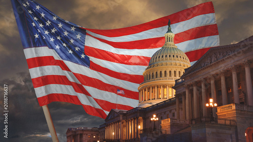  US Capitol building at night with an American flag in the background, Washington DC, USA. Happy 4th of July – Independence Day!