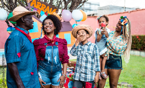 Happy multi-generational Black family celebrating Festa Junina at a traditional Brazilian Arraial party outdoors.