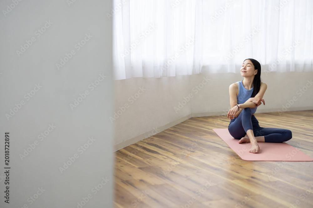 Obraz premium Asian Woman Smiling and Relaxing by a Bright Window