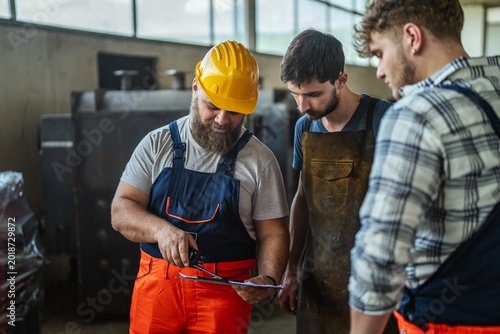 Bild auf Leinwand Experienced engineers mentoring young apprentices in industrial factory workplac