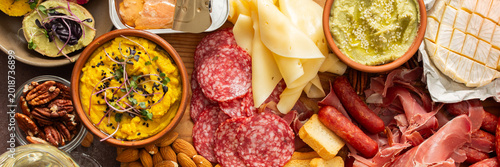Fotografie This festive spread features an array of cheese, cured meats, hummus, nuts, and fresh vegetables