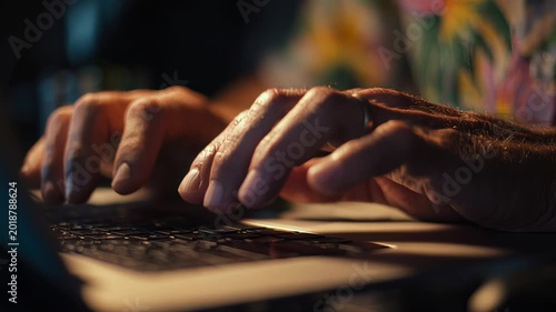 Close up of man's hands typing on laptop keyboard, neutral indoor setting, natural light, workspace detail