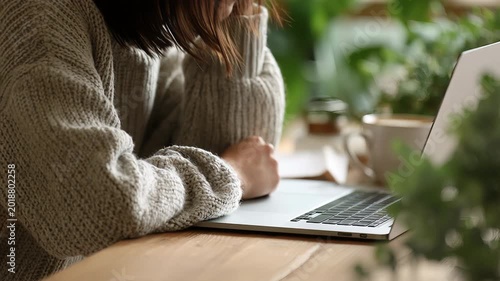 Close up of hands typing on laptop keyboard, browsing and searching online, warm indoor light, remote work concept