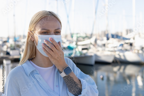 Konstfotografi Young woman covering her mouth while wearing a disposable medical face mask, fee