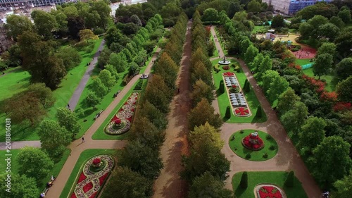 4K aerial view of Regent's Park Avenue Gardens with symmetrical Victorian flower parterres, tree-lined Broad Walk, stone fountains and Nash terraces in Central London.