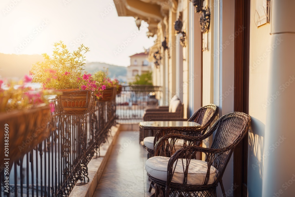 Naklejka premium Boutique Hotel Balcony with Outdoor Seating, Warm Sunrise or Sunset Light and Premium Travel-Focused Interior for Editorial and Commercial Use
