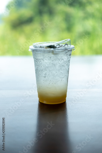 A glass of honey lemon soda on the wooden table, with bokeh background of the landscape
