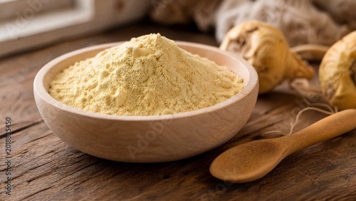 maca. A shallow wooden bowl filled with fine pale yellow maca powder and a spoon. menu design, packaging mockups, designed for culinary blogs and recipe cards for restaurants.