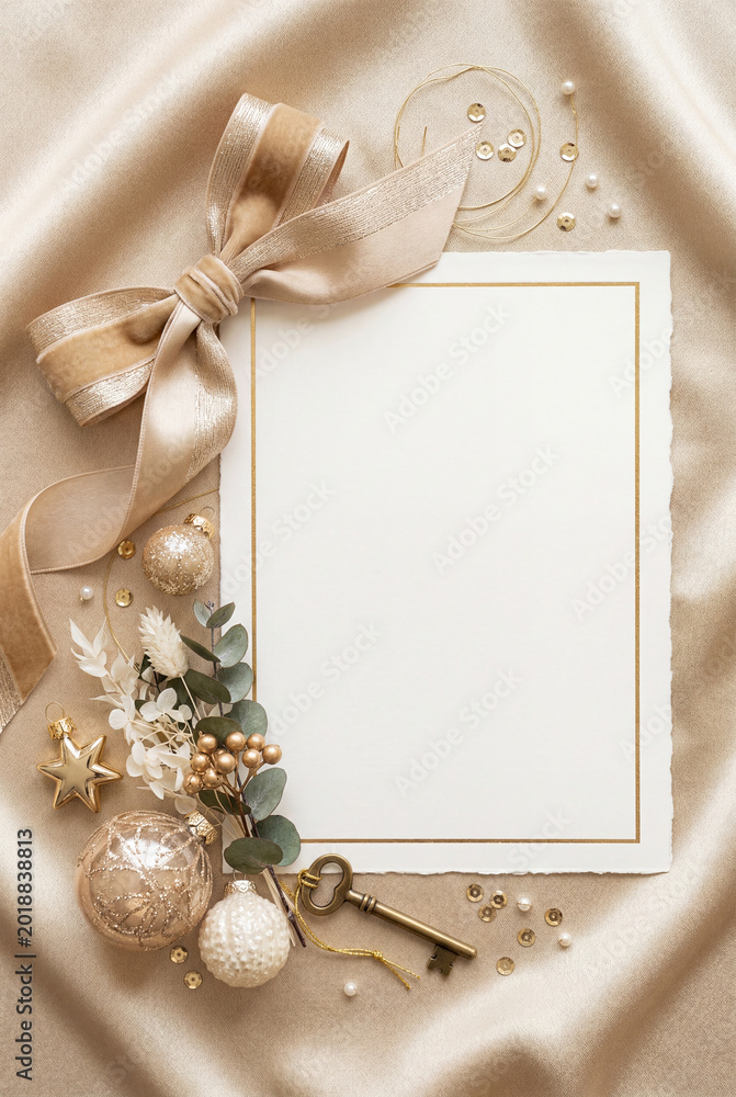 Fototapeta premium Luxury gold holiday invitation background with satin ribbon bow and ornaments for christmas and new year card design and stationery mockup