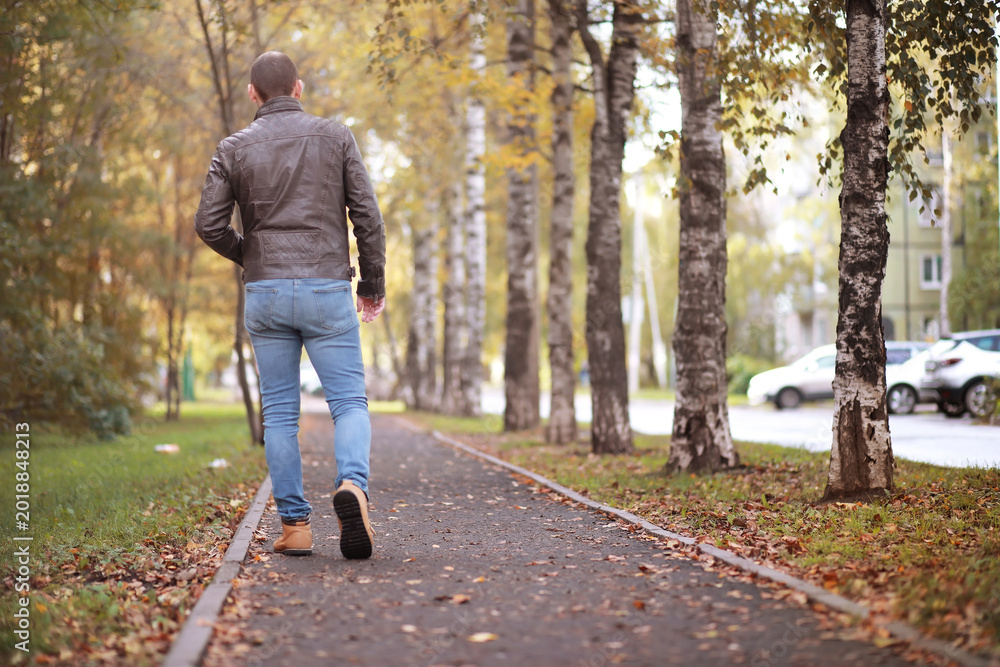 Obraz premium Autumn concept. Pedestrian feet on the road. Autumn leaves on the footpath.