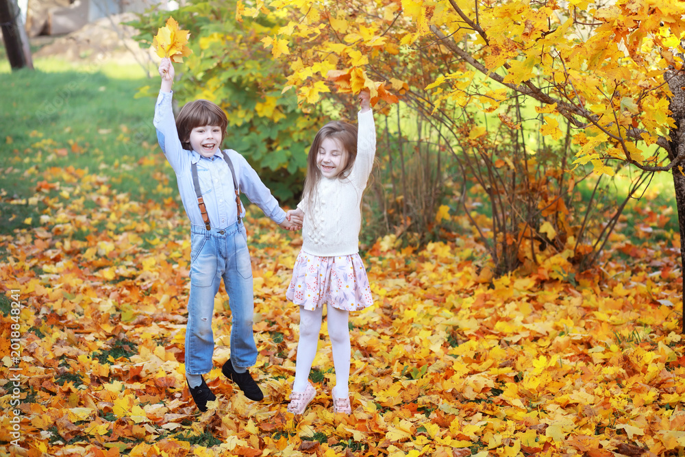 Naklejka premium Young family on a walk in the autumn park on a sunny day. Happiness to be together.