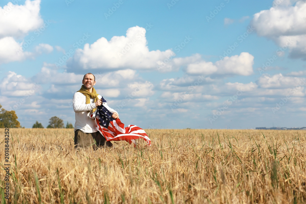 Obraz premium Man waving American flag standing in grass farm agricultural field , holidays, patriotism, pride, freedom, political parties, immigrant
