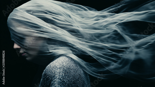 Woman face covered by flowing translucent fabric. Surreal concept of psychological disorder and emotional isolation. Abstract mental health metaphor for depression and confusion.