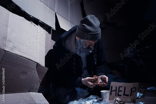 Quadro su tela A homeless bearded man sits on boxes on the street and asks for help